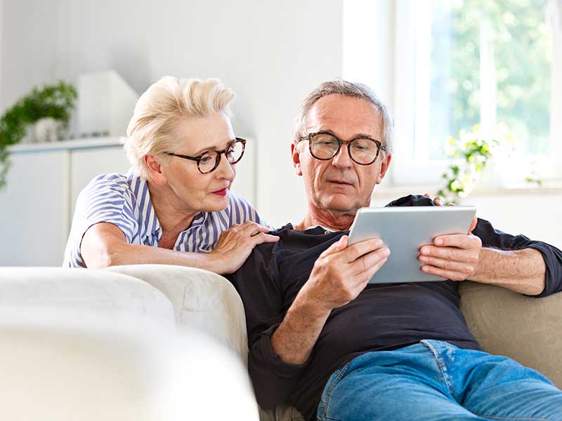 Senior couple watching digital tablet together at home Books Articles and Media